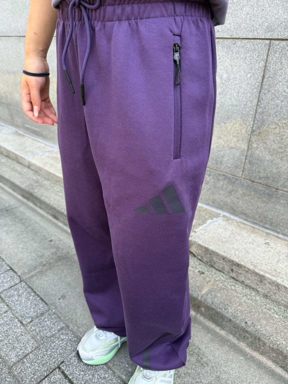 パープル系のTシャツ/カットソー、パープル系のパンツ、ホワイト系のスニーカーを着用したレディースの冬コーディネートの3枚目の写真