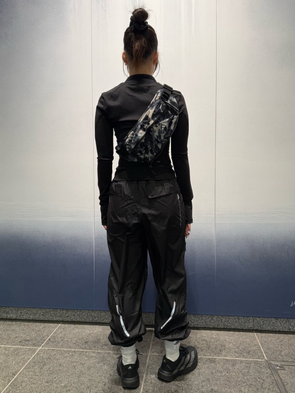 ブラック系のスニーカー、グレー系のボディバッグ/ウエストポーチ、ブラック系のジャケット/アウターを着用したレディースの冬コーディネートの2枚目の写真