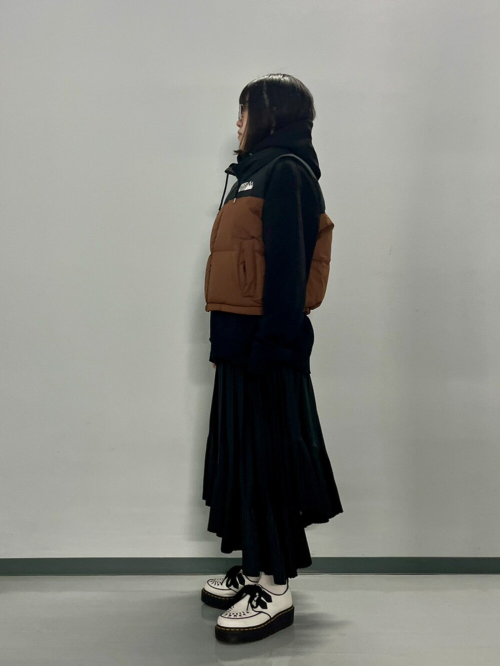 ブラウン系のダウンベスト、ブラック系のパーカーを着用したレディースの秋コーディネートの6枚目の写真