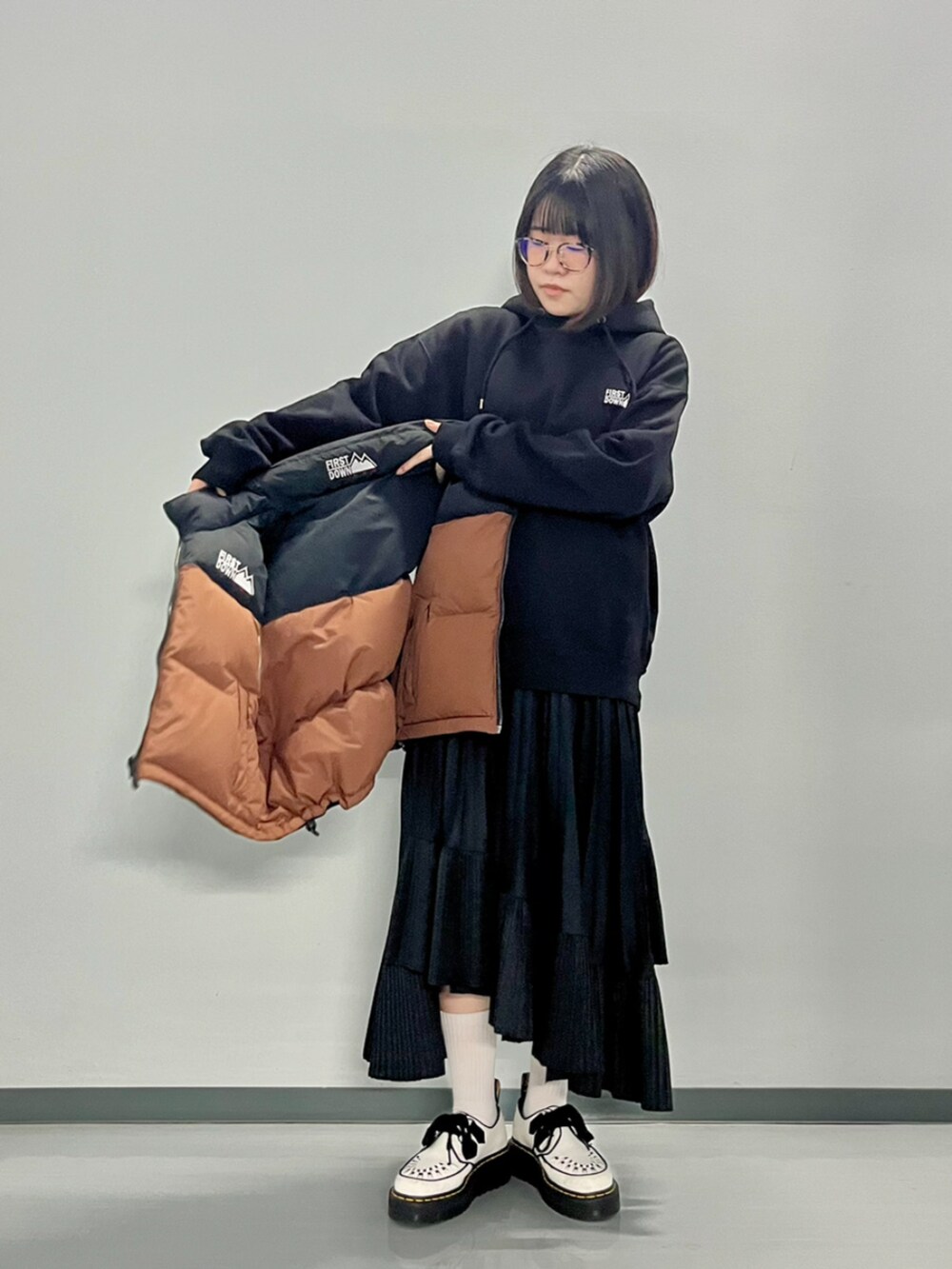 ブラウン系のダウンベスト、ブラック系のパーカーを着用したレディースの秋コーディネートの7枚目の写真