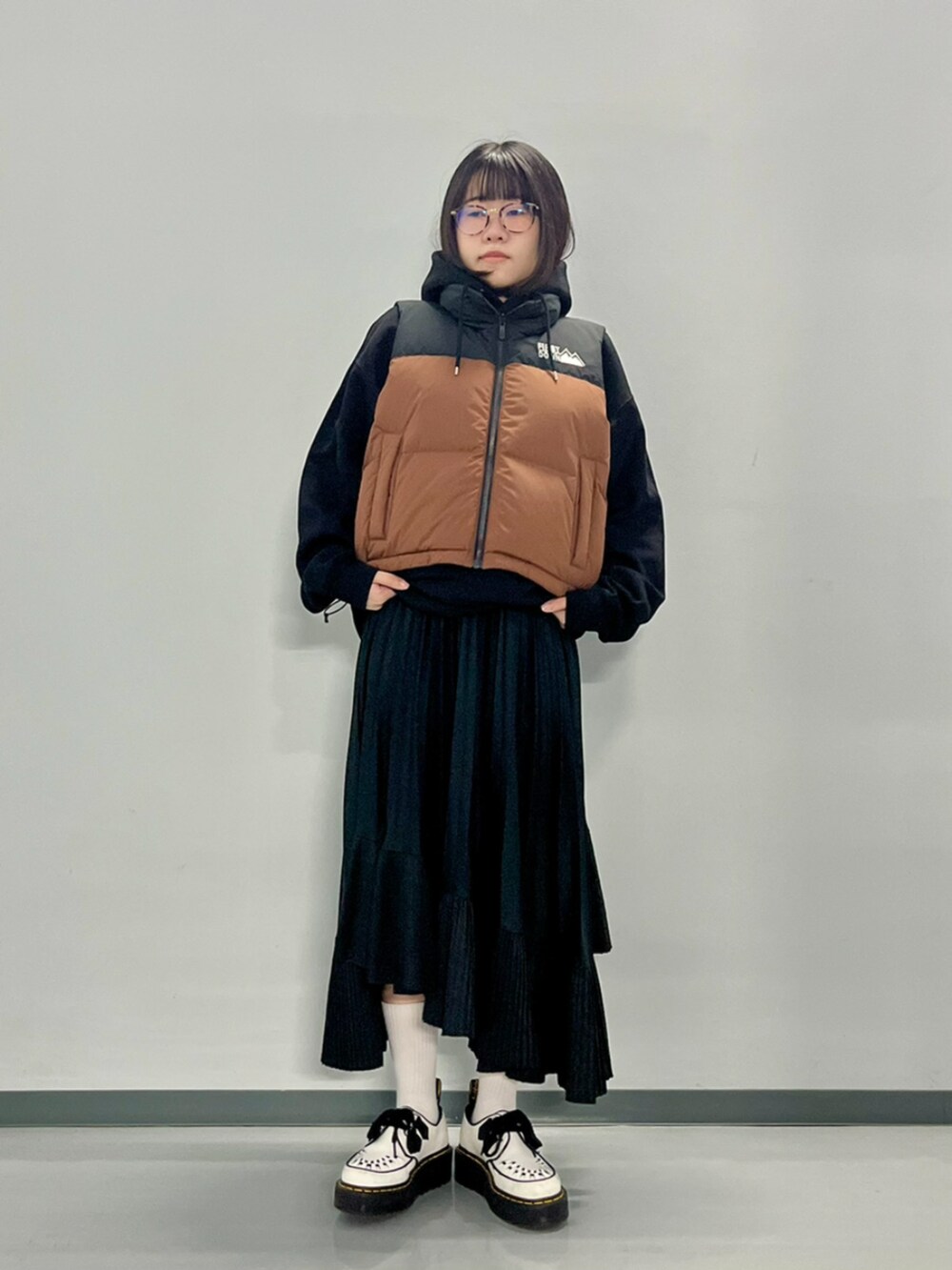 ブラウン系のダウンベスト、ブラック系のパーカーを着用したレディースの秋コーディネートの3枚目の写真