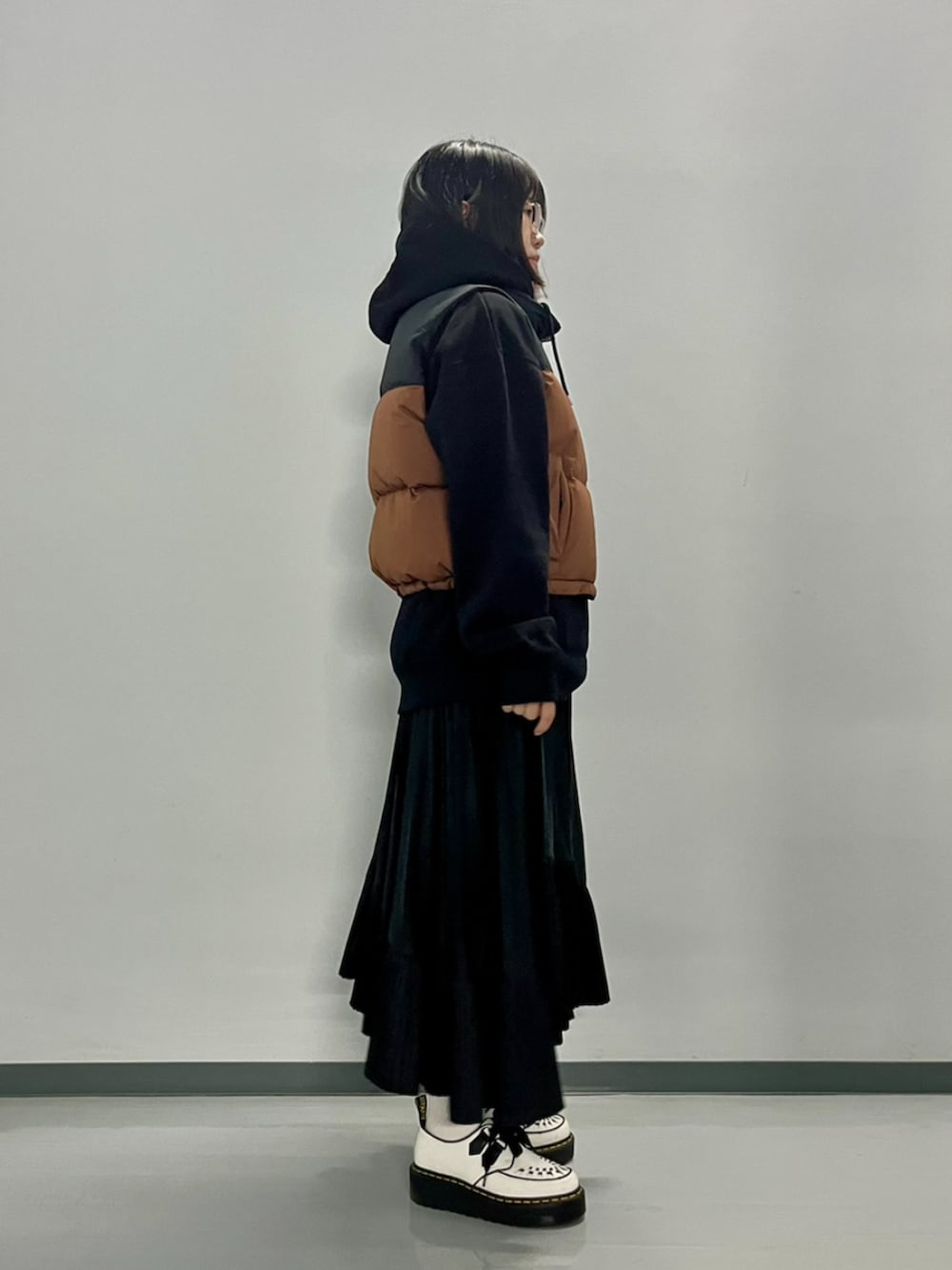 ブラウン系のダウンベスト、ブラック系のパーカーを着用したレディースの秋コーディネートの4枚目の写真