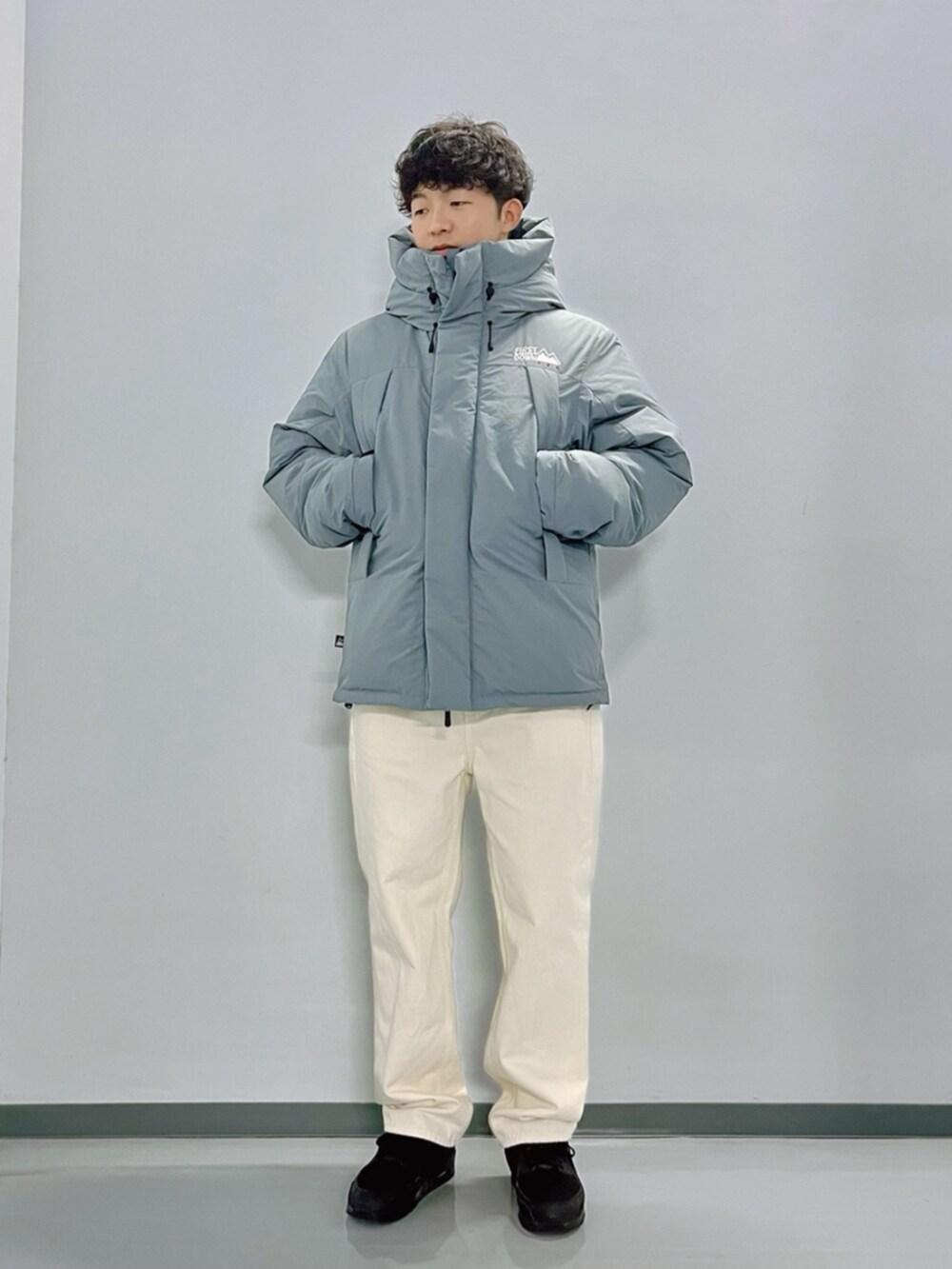 グレー系のダウンジャケット/コート、ブラック系のスウェット、ホワイト系のデニムパンツを着用したメンズの秋コーディネートの4枚目の写真