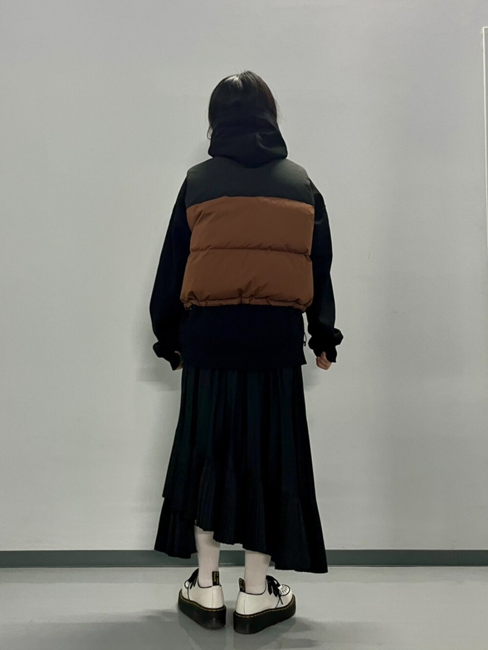 ブラウン系のダウンベスト、ブラック系のパーカーを着用したレディースの秋コーディネートの5枚目の写真