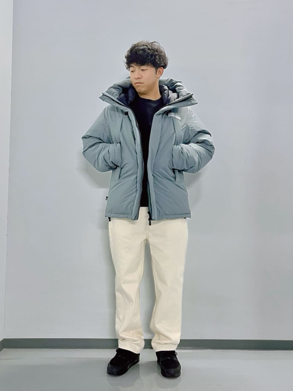 グレー系のダウンジャケット/コート、ブラック系のスウェット、ホワイト系のデニムパンツを着用したメンズの秋コーディネートの3枚目の写真