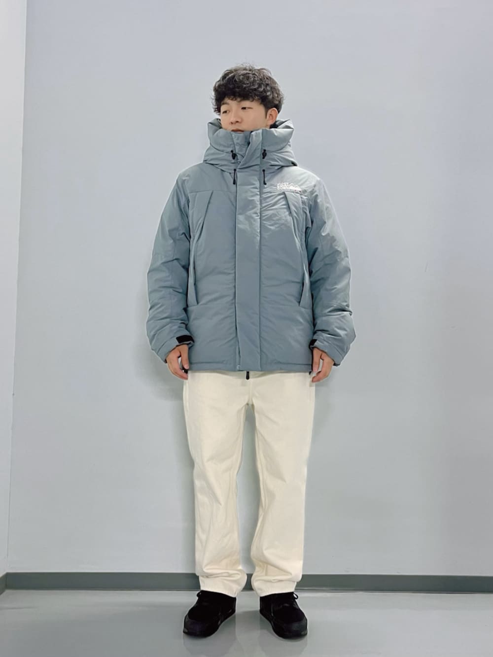 グレー系のダウンジャケット/コート、ブラック系のスウェット、ホワイト系のデニムパンツを着用したメンズの秋コーディネートの5枚目の写真