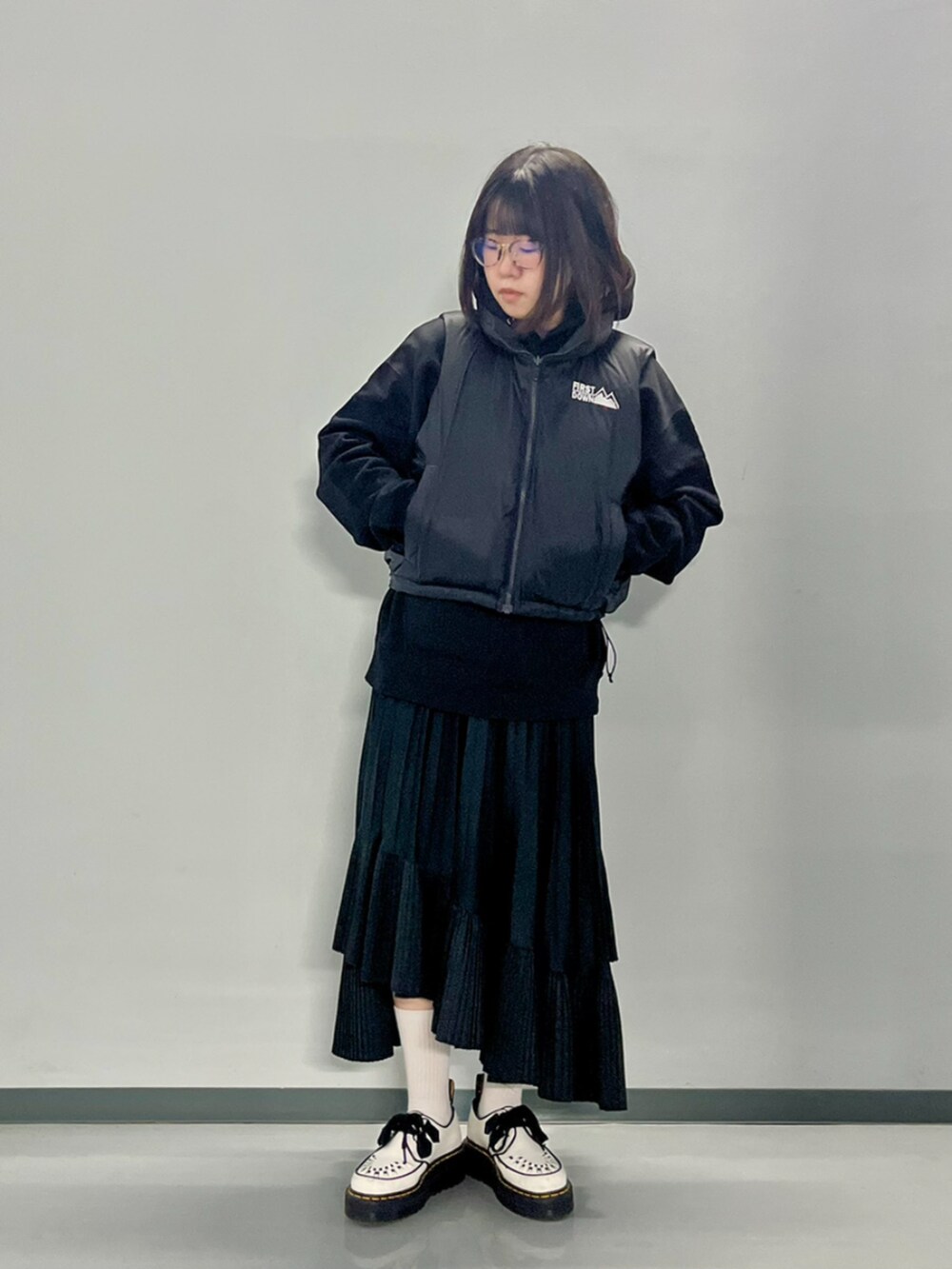 ブラウン系のダウンベスト、ブラック系のパーカーを着用したレディースの秋コーディネートの9枚目の写真