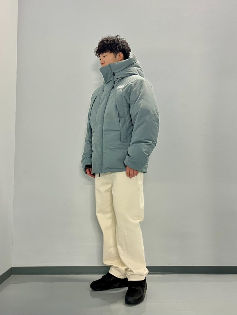 グレー系のダウンジャケット/コート、ブラック系のスウェット、ホワイト系のデニムパンツを着用したメンズの秋コーディネートの6枚目の写真