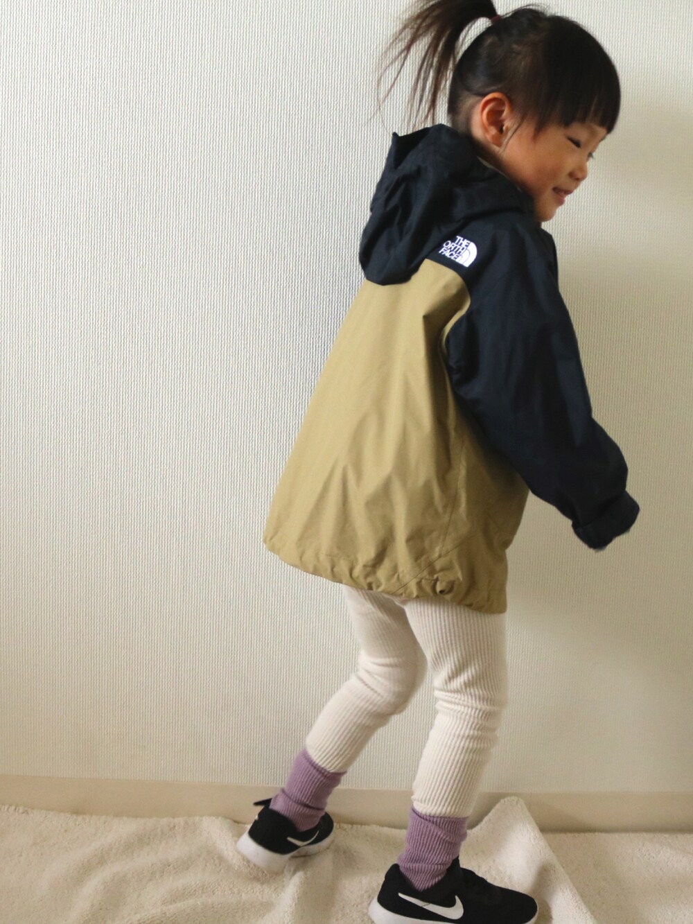 ベージュ系のその他アウター、ブラック系のスニーカーを着用したキッズの冬コーディネートの2枚目の写真