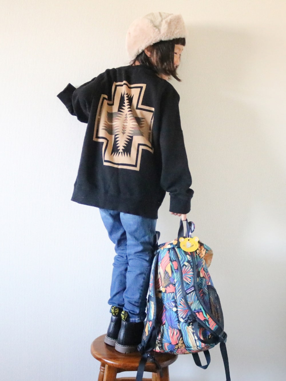 ブルー系のデニムパンツ、ブラック系のブーツ、ブラック系のスウェットを着用したキッズの冬コーディネートの3枚目の写真