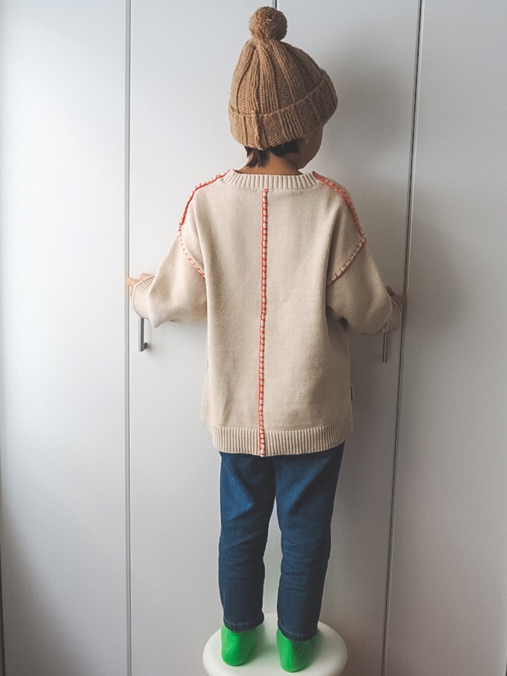 ブルー系のデニムパンツ、ベージュ系のニット/セーター、グリーン系のソックス/靴下を着用したキッズの冬コーディネートの2枚目の写真