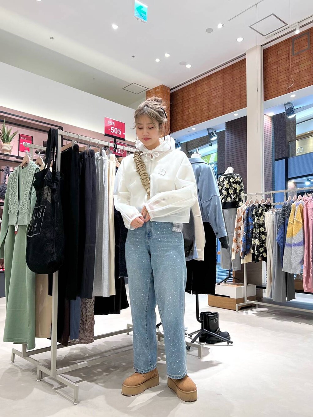 ブルー系のデニムパンツ、ホワイト系のニット/セーター、ホワイト系のパーカーを着用したレディースの冬コーディネートの2枚目の写真