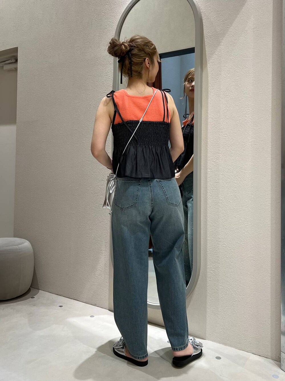 オレンジ系のタンクトップ、ブルー系のデニムパンツ、シルバー系のショルダーバッグを着用したレディースの夏コーディネートの3枚目の写真
