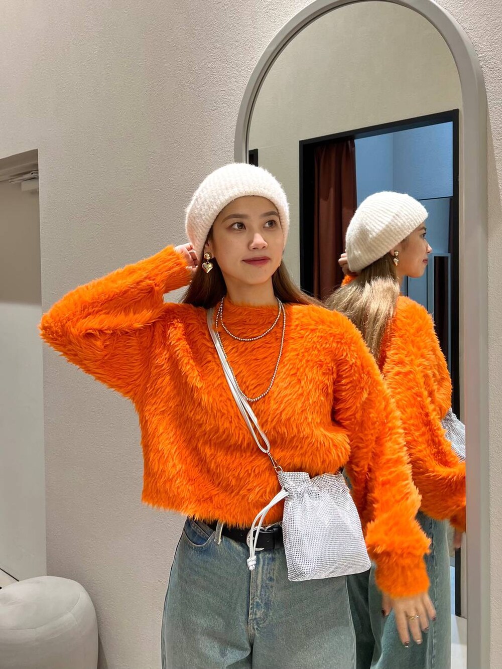 ブルー系のデニムパンツ、ホワイト系のブーツ、シルバー系のボストンバッグを着用したレディースの秋コーディネートの2枚目の写真