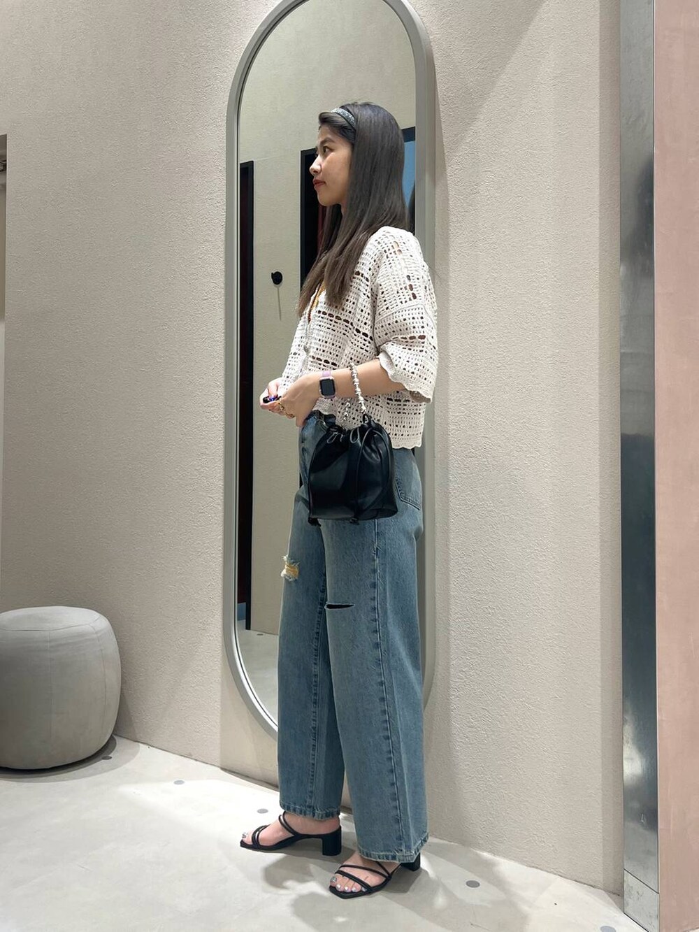 ブラック系のサンダル、シルバー系のショルダーバッグ、ブルー系のデニムパンツを着用したレディースの春コーディネートの2枚目の写真