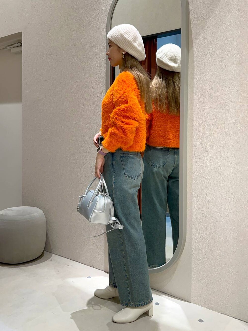 ブルー系のデニムパンツ、ホワイト系のブーツ、シルバー系のボストンバッグを着用したレディースの秋コーディネートの3枚目の写真