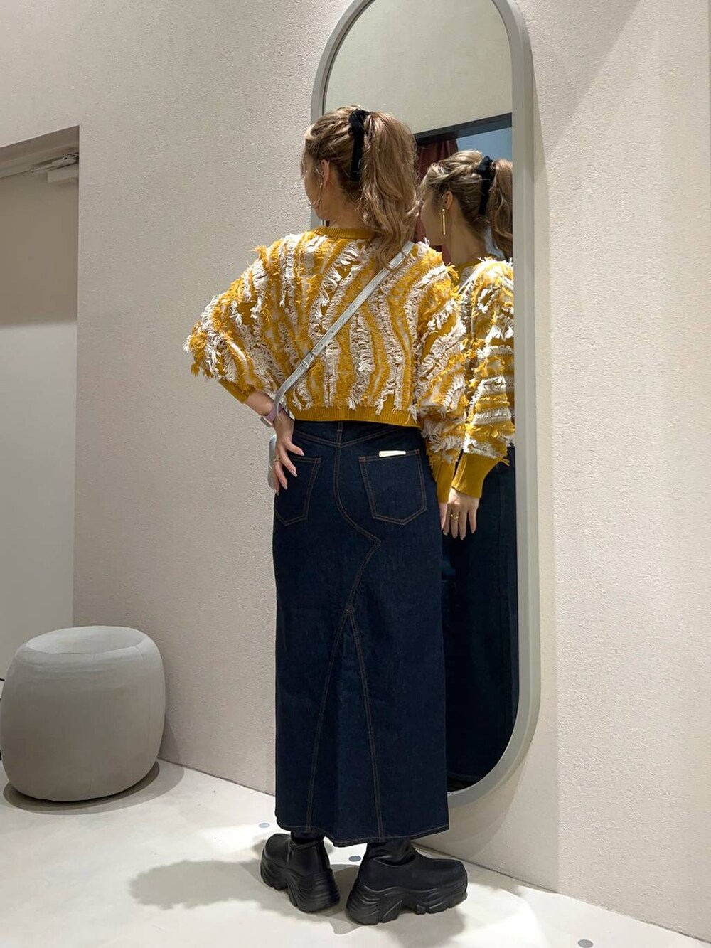 ブルー系のスカート、シルバー系のボストンバッグ、イエロー系のニット/セーターを着用したレディースの秋コーディネートの3枚目の写真