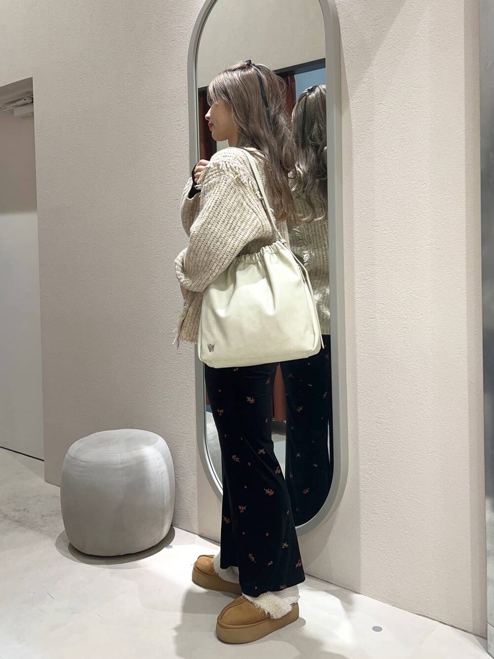 ホワイト系のニット/セーター、ホワイト系のショルダーバッグ、ブラック系のTシャツ/カットソーを着用したレディースの冬コーディネートの2枚目の写真