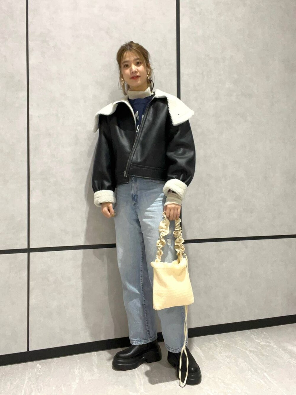 ブルー系のデニムパンツ、ブラック系のブルゾン、ブラック系のブーツを着用したレディースの秋コーディネートの2枚目の写真