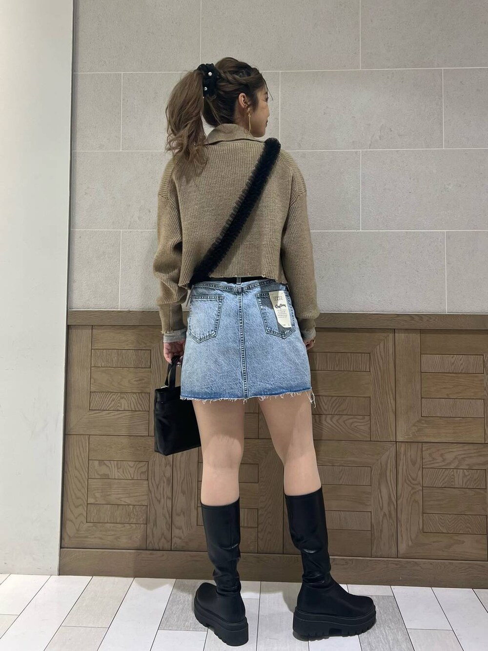 ブラック系のショルダーバッグ、ブラック系のブーツ、ホワイト系のTシャツ/カットソーを着用したレディースの冬コーディネートの3枚目の写真