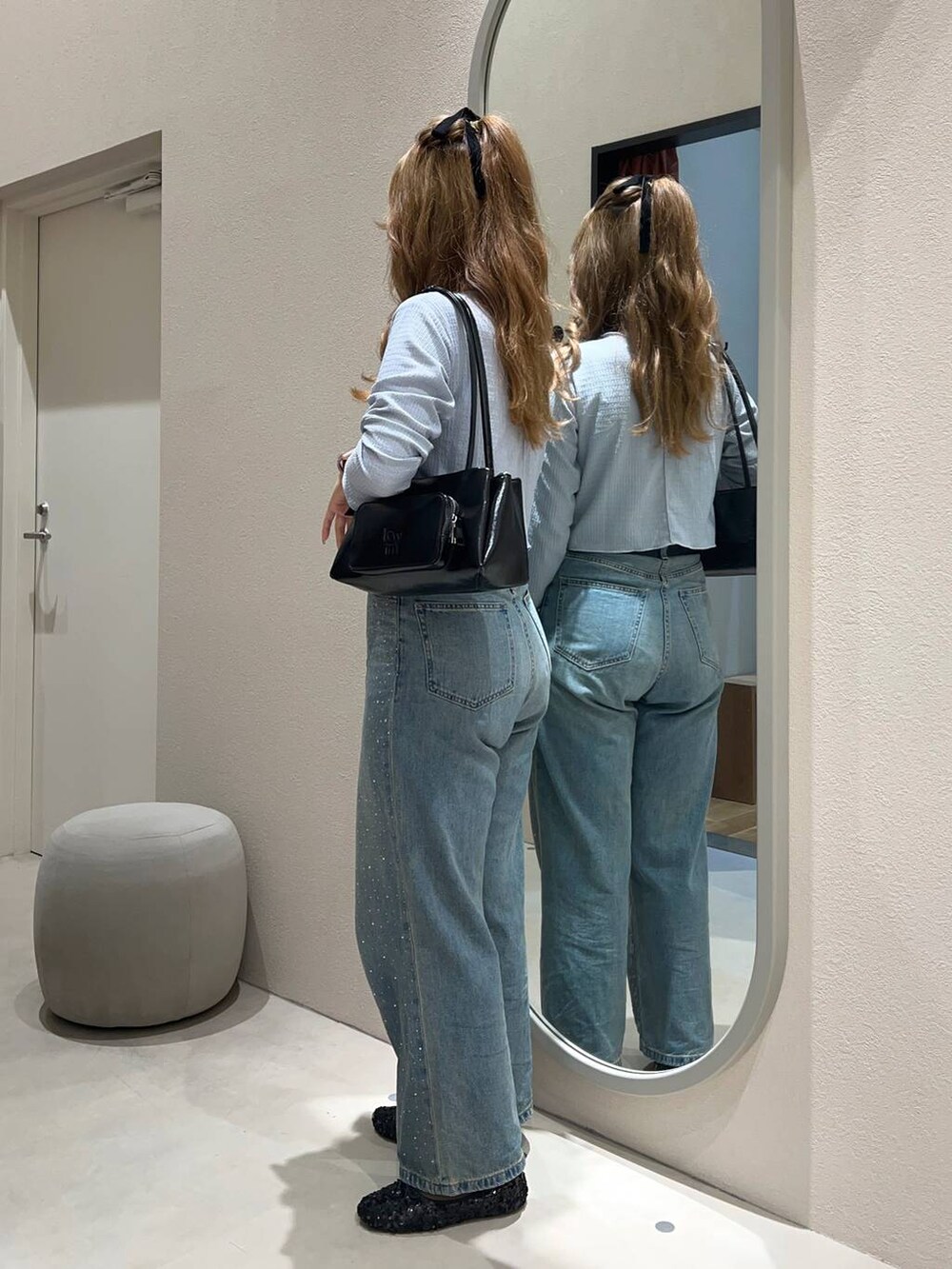 ブルー系のデニムパンツ、ブラック系のショルダーバッグ、ブラック系のバレエシューズを着用したレディースの秋コーディネートの2枚目の写真