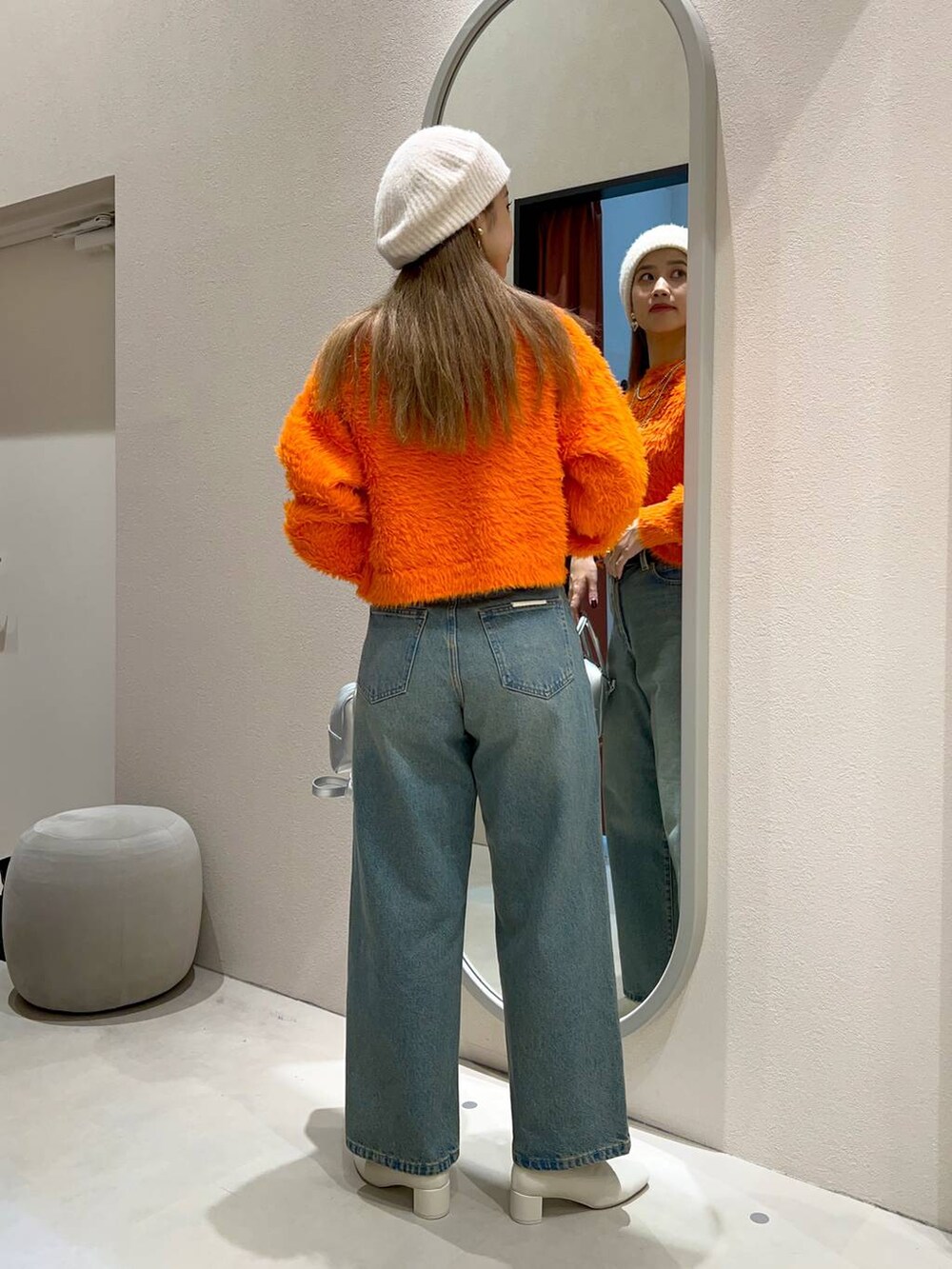 ブルー系のデニムパンツ、ホワイト系のブーツ、シルバー系のボストンバッグを着用したレディースの秋コーディネートの4枚目の写真