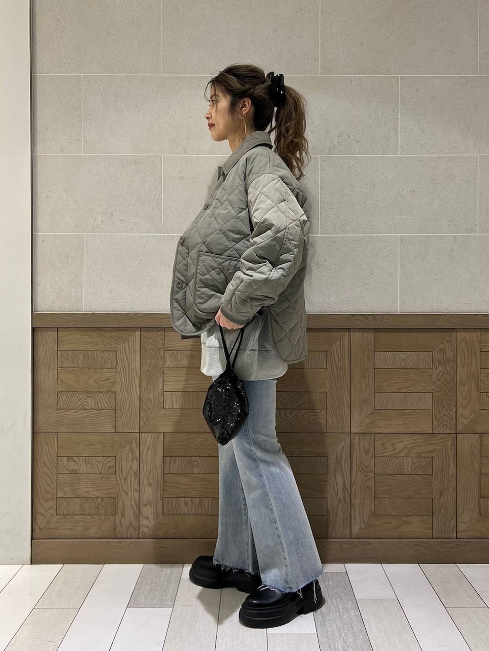 ブラック系のブーツ、ブラック系のハンドバッグ、グリーン系のブルゾンを着用したレディースの冬コーディネートの2枚目の写真