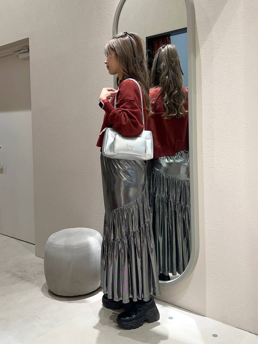 ブラック系のブーツ、シルバー系のショルダーバッグ、グレー系のスカートを着用したレディースの冬コーディネートの2枚目の写真