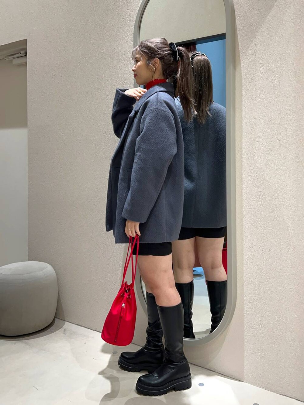ブラック系のブーツ、グレー系のスウェット、レッド系のハンドバッグを着用したレディースの冬コーディネートの2枚目の写真