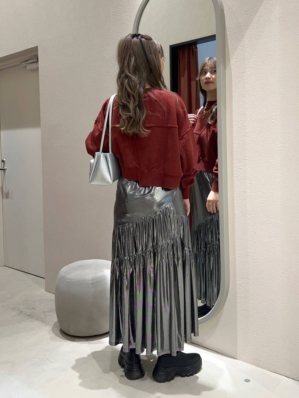 ブラック系のブーツ、シルバー系のショルダーバッグ、グレー系のスカートを着用したレディースの冬コーディネートの3枚目の写真