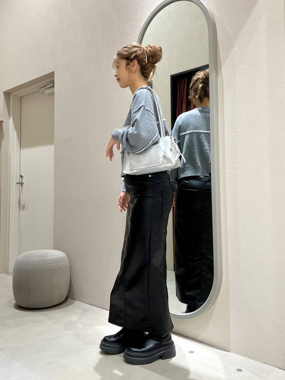 グレー系のスウェット、シルバー系のショルダーバッグ、ブラック系のジャンパースカートを着用したレディースの秋コーディネートの2枚目の写真