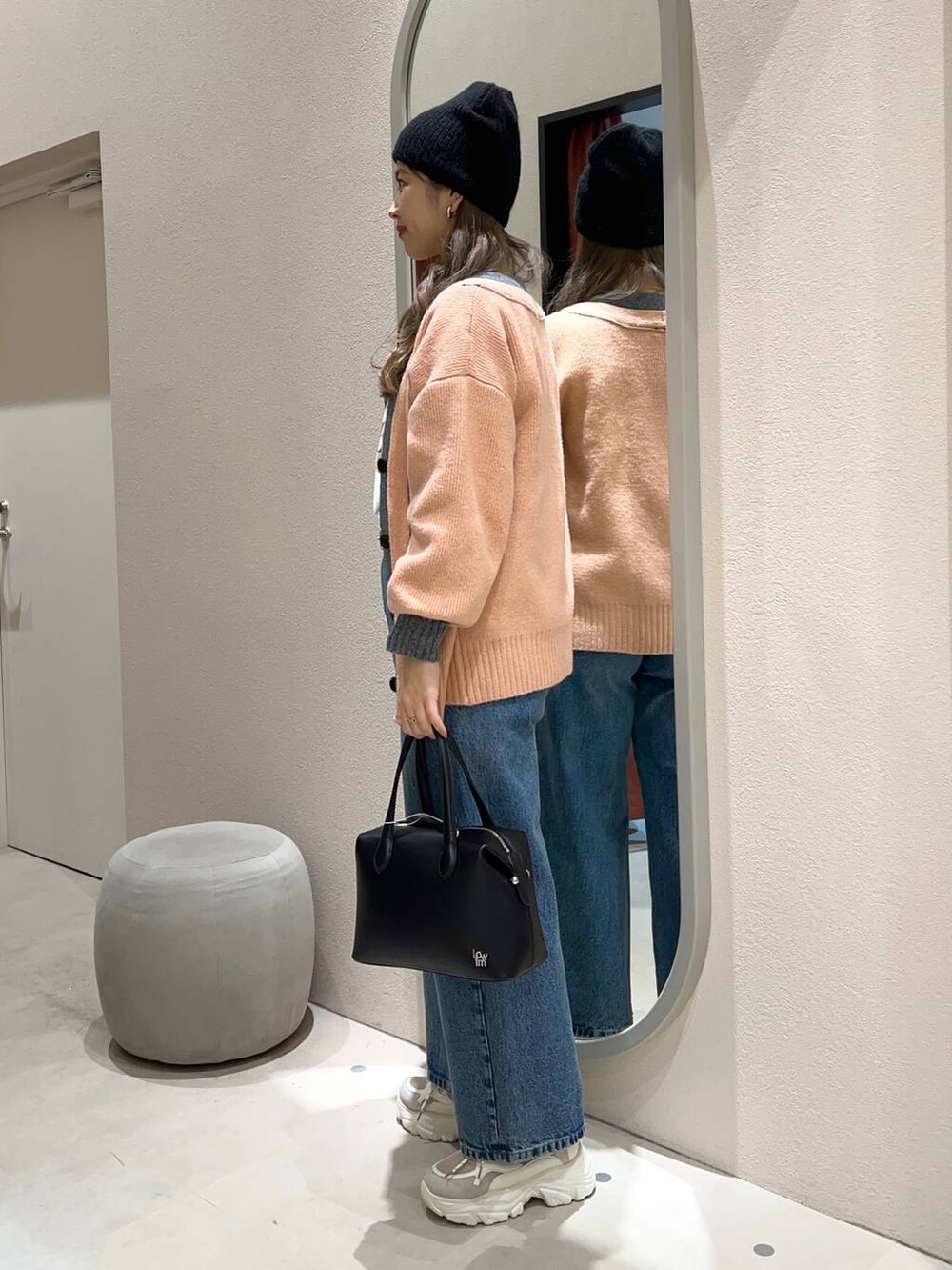 ブルー系のデニムパンツ、ブラック系のショルダーバッグ、ベージュ系のスニーカーを着用したレディースの冬コーディネートの2枚目の写真