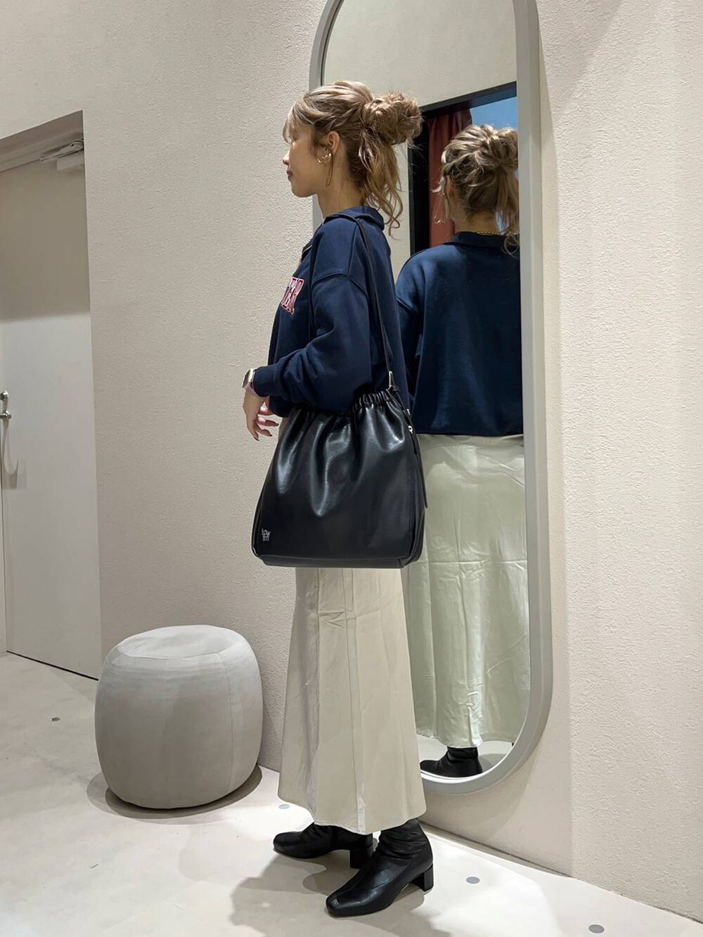 ホワイト系のスカート、ブラック系のブーツ、ブルー系のスウェットを着用したレディースの秋コーディネートの2枚目の写真