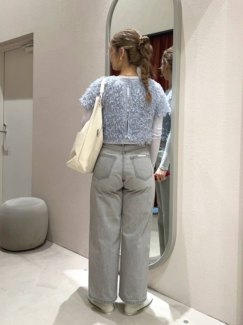 グレー系のデニムパンツ、ホワイト系のトートバッグ、ホワイト系のスニーカーを着用したレディースの冬コーディネートの3枚目の写真