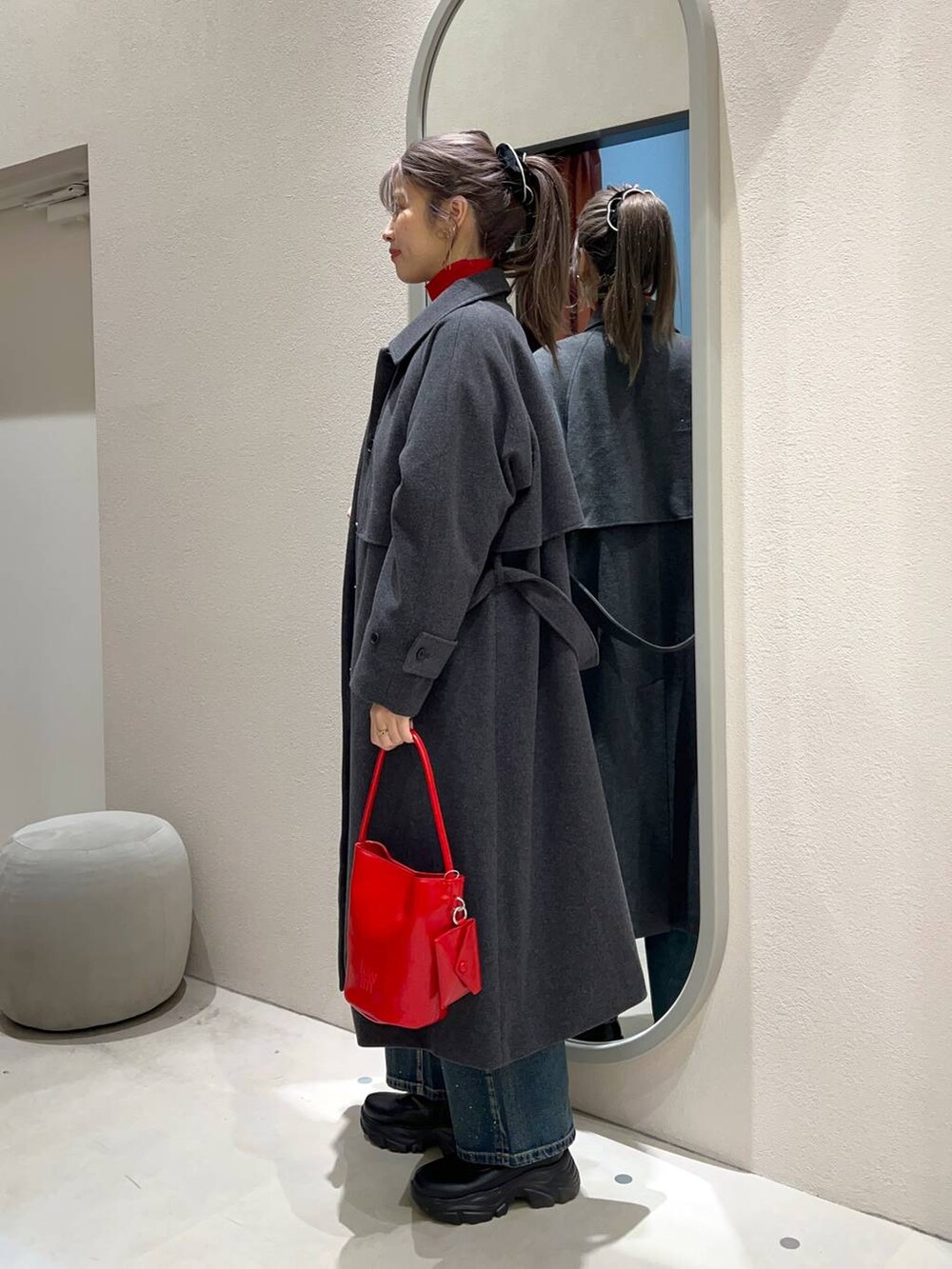 レッド系のニット/セーター、ブラック系のブーツ、ブルー系のデニムパンツを着用したレディースの冬コーディネートの2枚目の写真