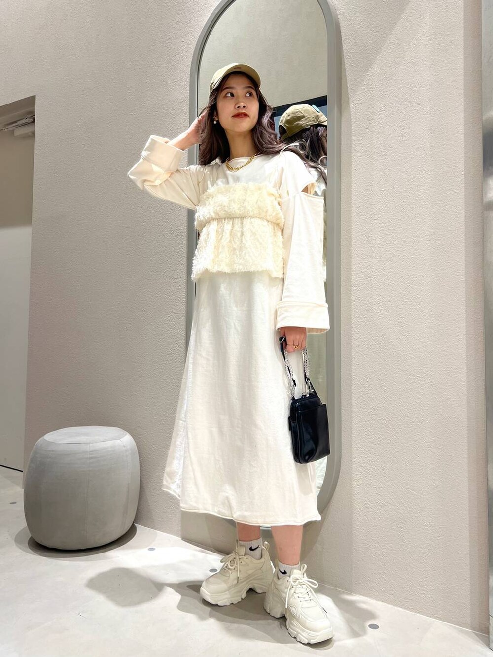 ブラック系のスマホグッズ、ベージュ系のキャップ、ゴールド系のリングを着用したレディースの春コーディネートの2枚目の写真