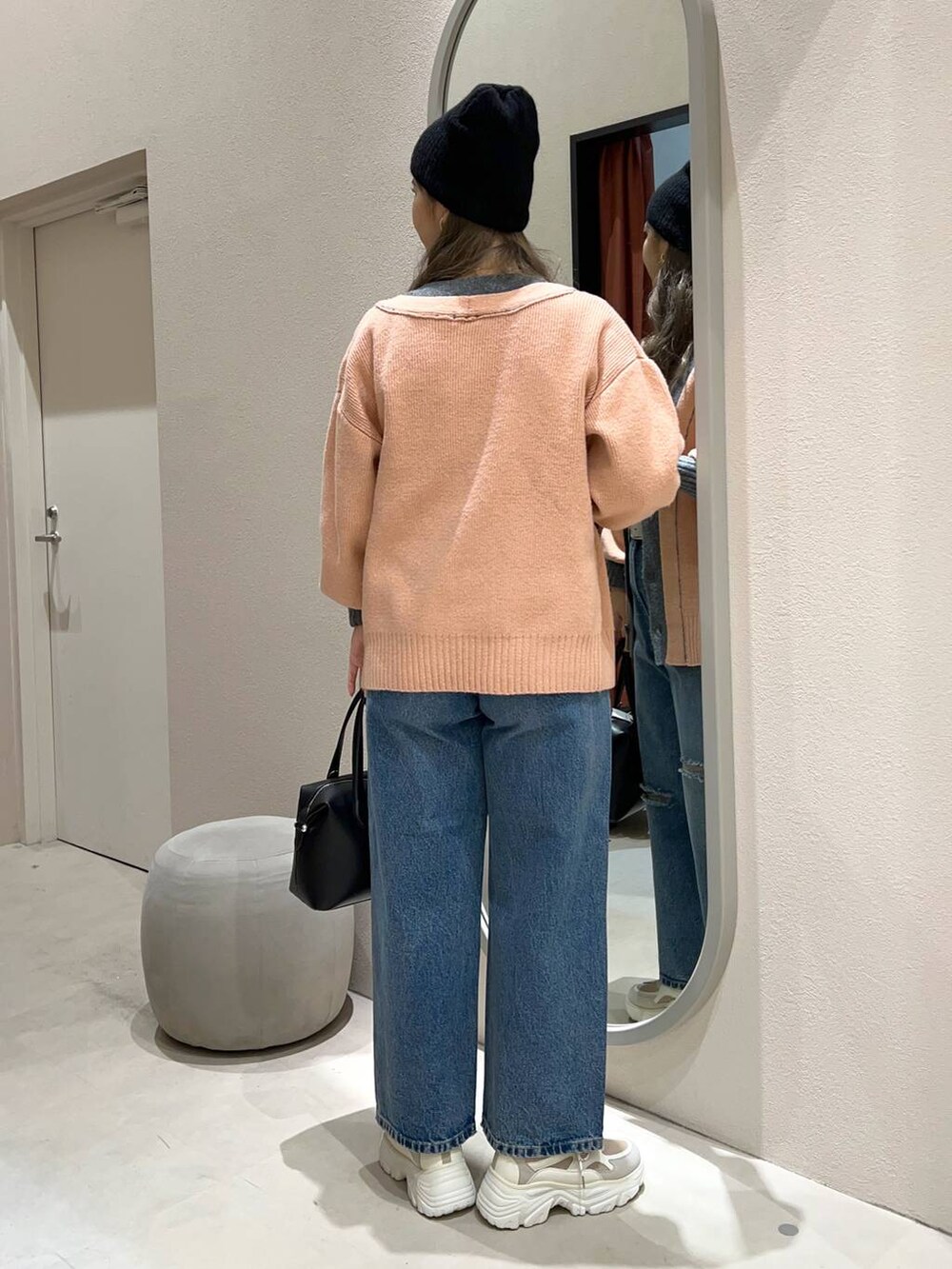 ブルー系のデニムパンツ、ブラック系のショルダーバッグ、ベージュ系のスニーカーを着用したレディースの冬コーディネートの3枚目の写真