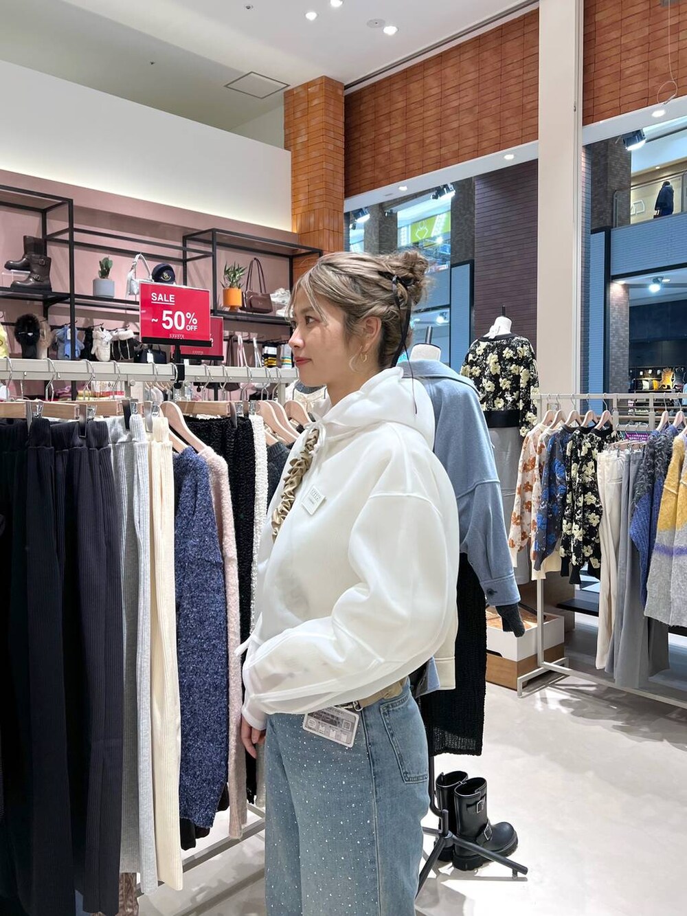 ブルー系のデニムパンツ、ホワイト系のニット/セーター、ホワイト系のパーカーを着用したレディースの冬コーディネートの3枚目の写真