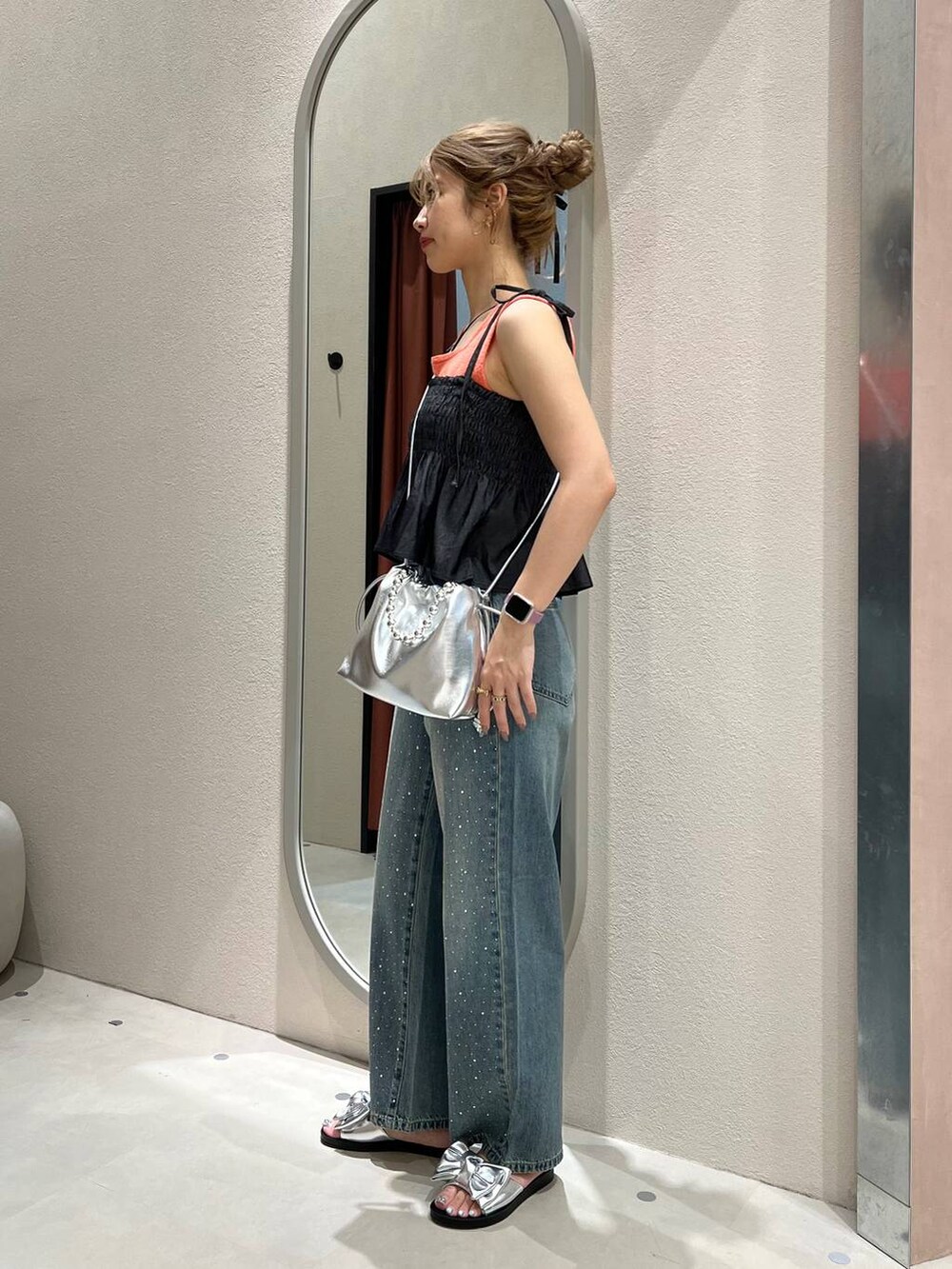 オレンジ系のタンクトップ、ブルー系のデニムパンツ、シルバー系のショルダーバッグを着用したレディースの夏コーディネートの2枚目の写真