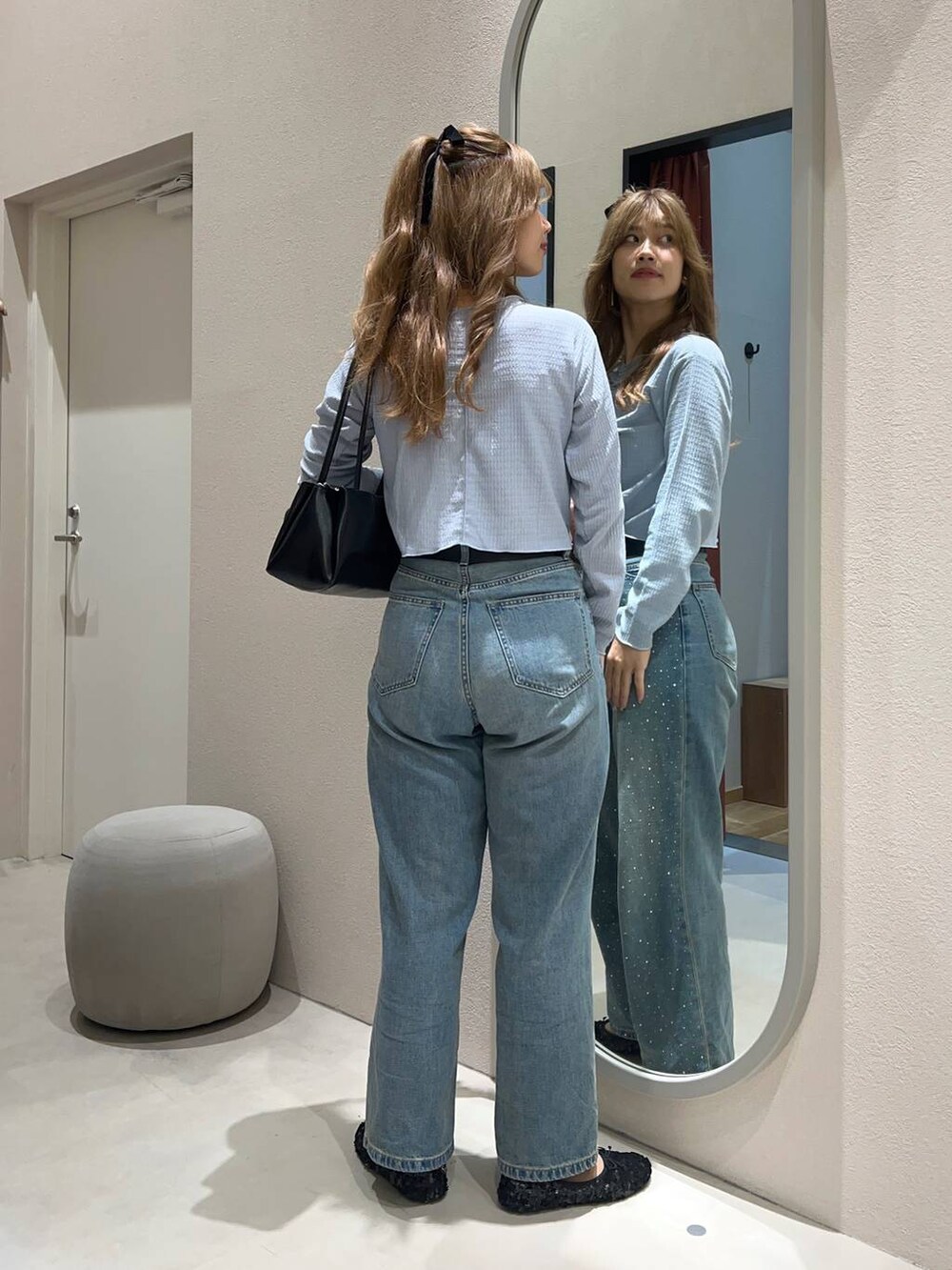 ブルー系のデニムパンツ、ブラック系のショルダーバッグ、ブラック系のバレエシューズを着用したレディースの秋コーディネートの3枚目の写真