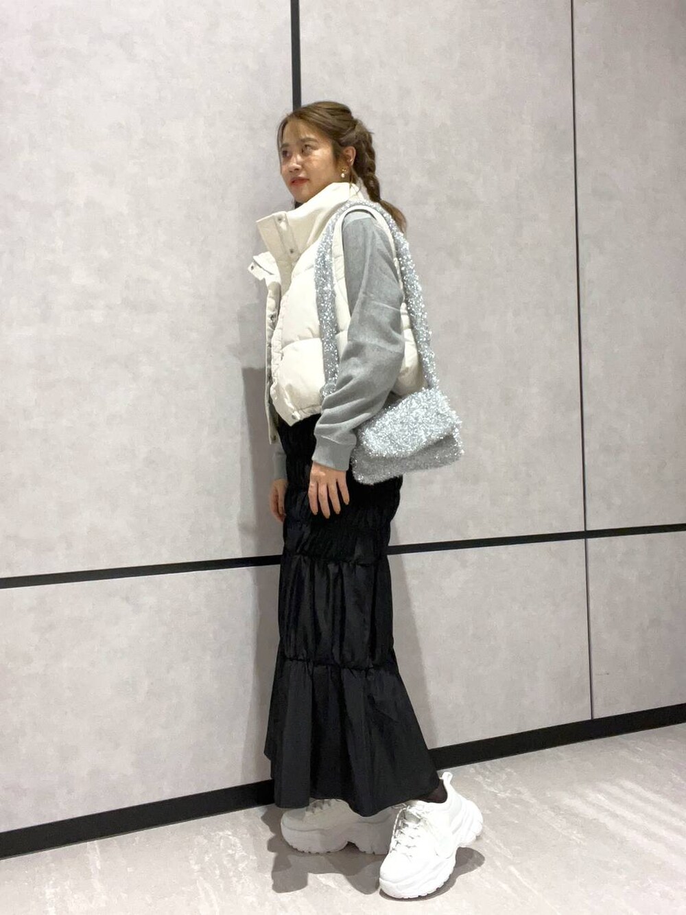 ホワイト系のダウンベスト、グレー系のスウェット、シルバー系のショルダーバッグを着用したレディースの秋コーディネートの2枚目の写真