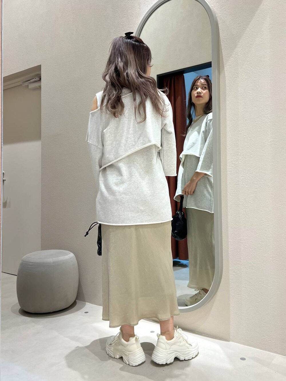 グリーン系のスカート、ホワイト系のスニーカー、ブラック系のハンドバッグを着用したレディースの冬コーディネートの3枚目の写真