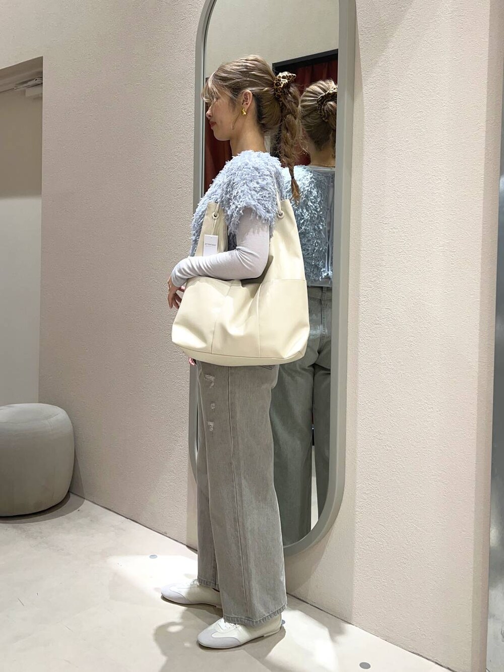 グレー系のデニムパンツ、ホワイト系のトートバッグ、ホワイト系のスニーカーを着用したレディースの冬コーディネートの2枚目の写真