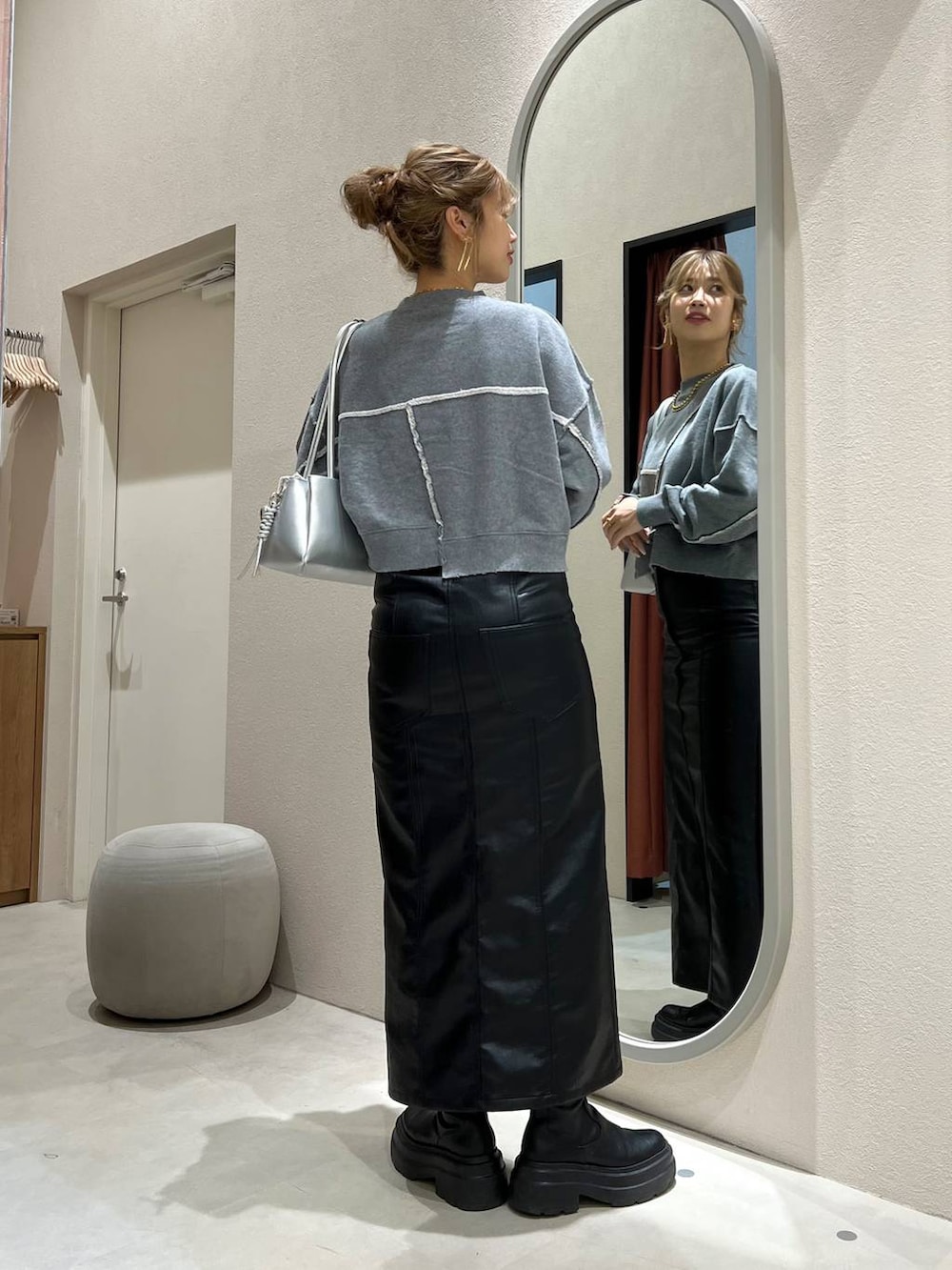 グレー系のスウェット、シルバー系のショルダーバッグ、ブラック系のジャンパースカートを着用したレディースの秋コーディネートの3枚目の写真