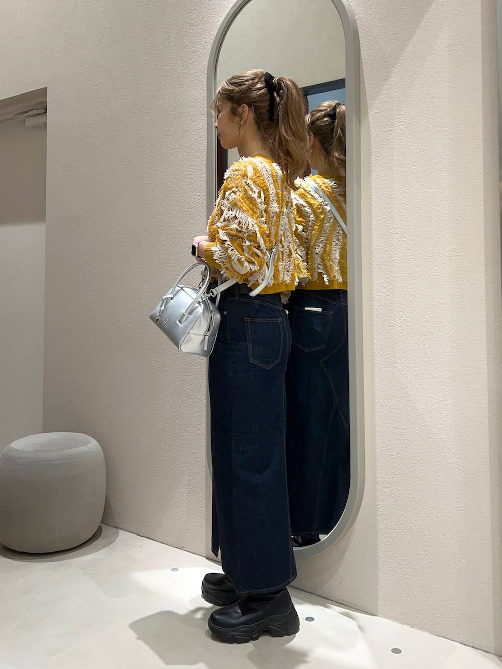 ブルー系のスカート、シルバー系のボストンバッグ、イエロー系のニット/セーターを着用したレディースの秋コーディネートの2枚目の写真