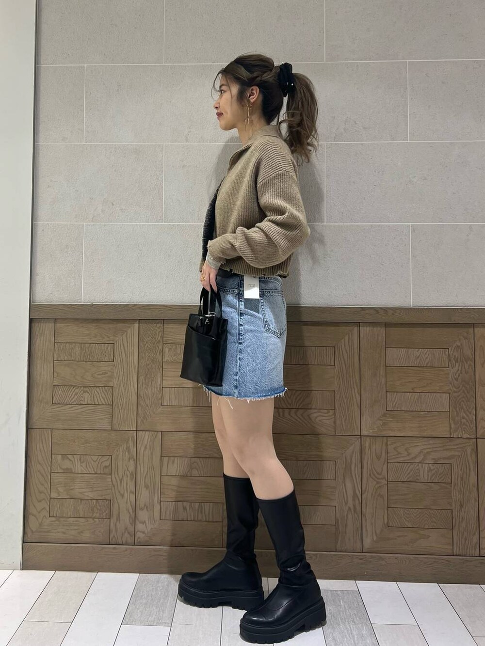 ブラック系のショルダーバッグ、ブラック系のブーツ、ホワイト系のTシャツ/カットソーを着用したレディースの冬コーディネートの2枚目の写真