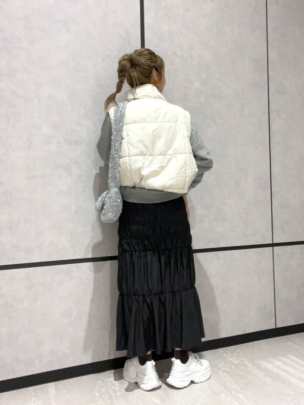 ホワイト系のダウンベスト、グレー系のスウェット、シルバー系のショルダーバッグを着用したレディースの秋コーディネートの3枚目の写真