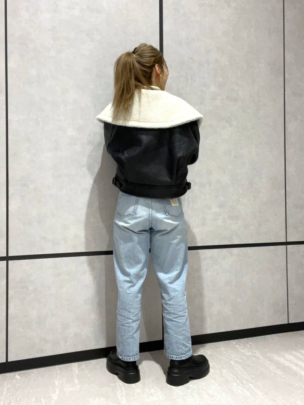 ブルー系のデニムパンツ、ブラック系のブルゾン、ブラック系のブーツを着用したレディースの秋コーディネートの3枚目の写真