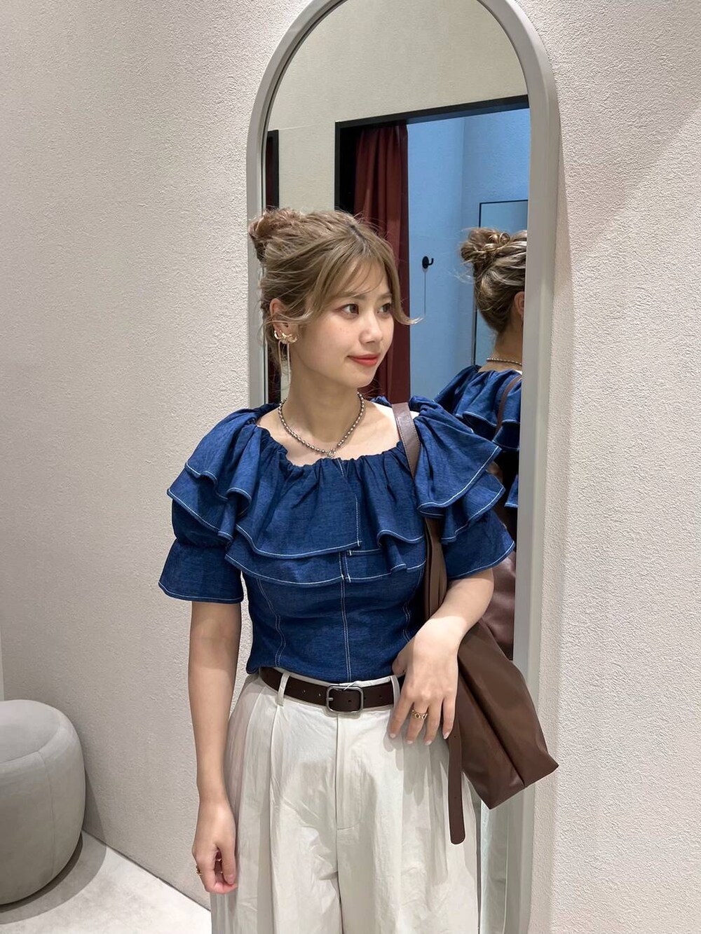 ブラウン系のショルダーバッグ、ホワイト系のスラックス、ホワイト系のスニーカーを着用したレディースの冬コーディネートの2枚目の写真