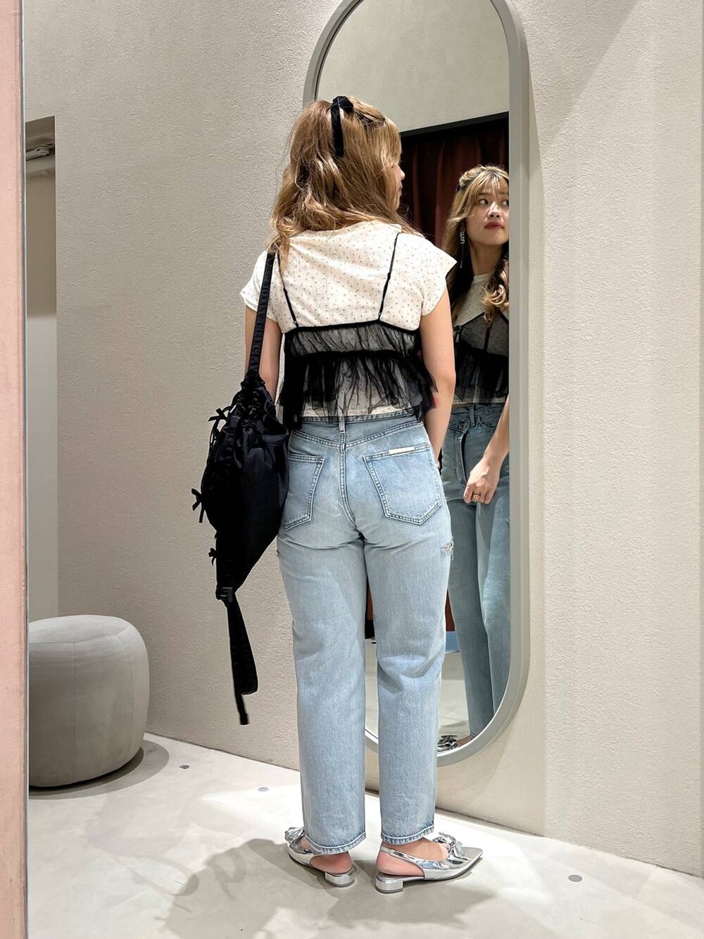 シルバー系のパンプス、ブラック系のベスト、ブルー系のデニムパンツを着用したレディースの夏コーディネートの3枚目の写真